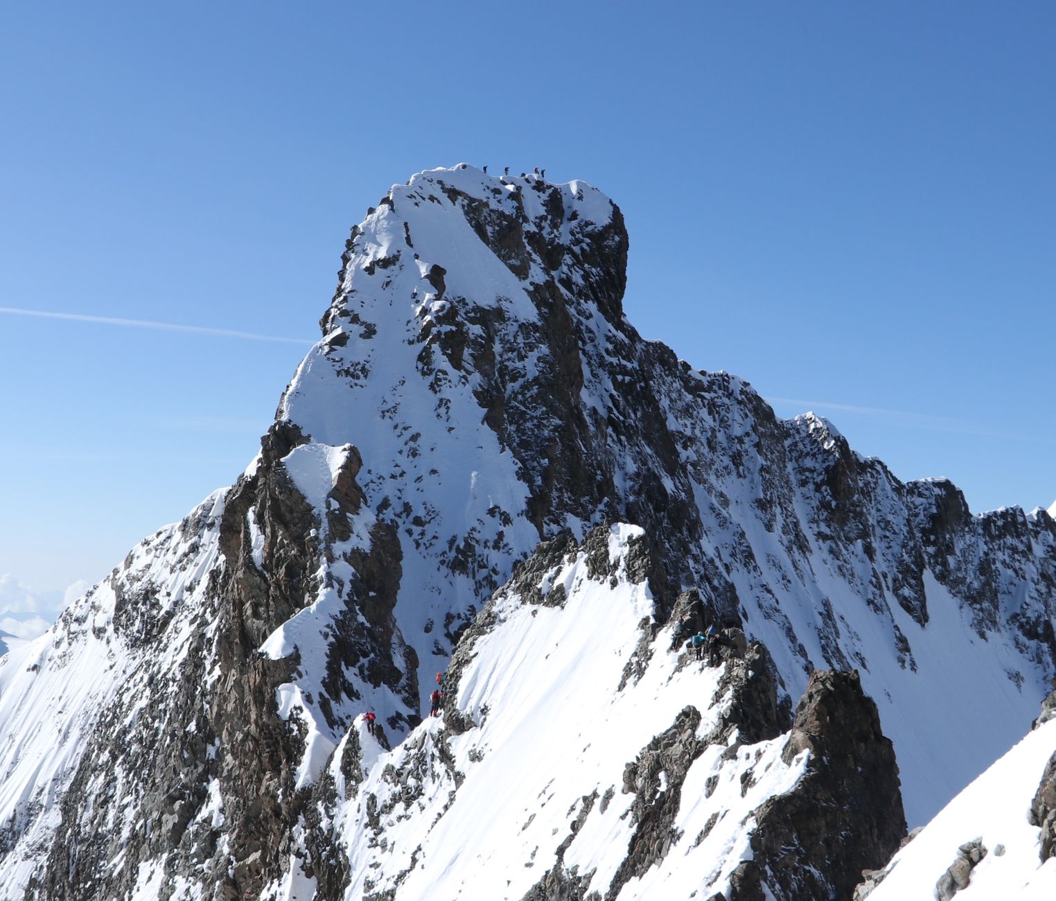 Climber on a knife-edge snowy ridge in the Alps
